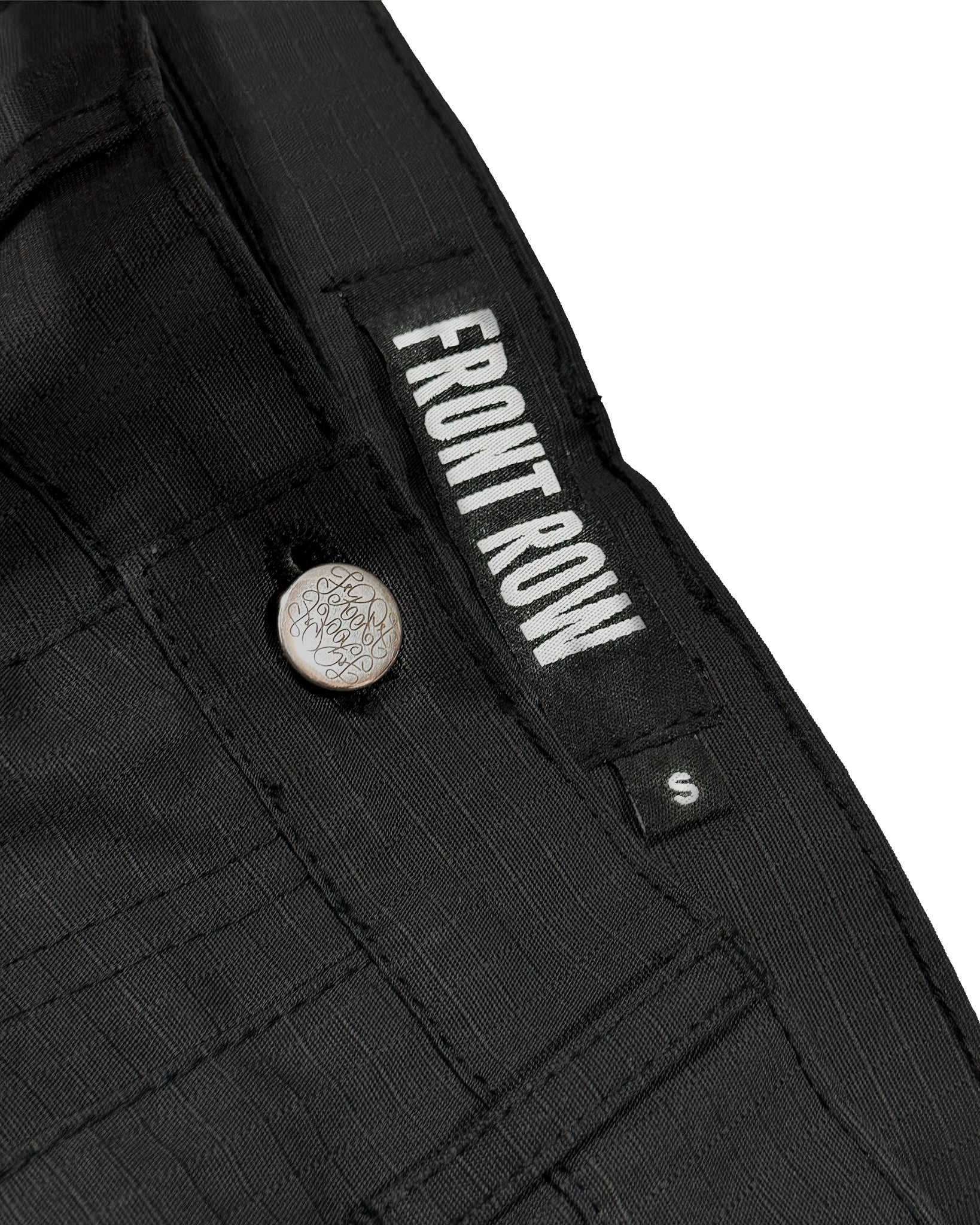 Pantalón cargo negro oversize de ripstop, corte tres cuartos unisex, bolsillos laterales grandes y cinturón ajustable, estilo streetwear/techwear resistente y cómodo.