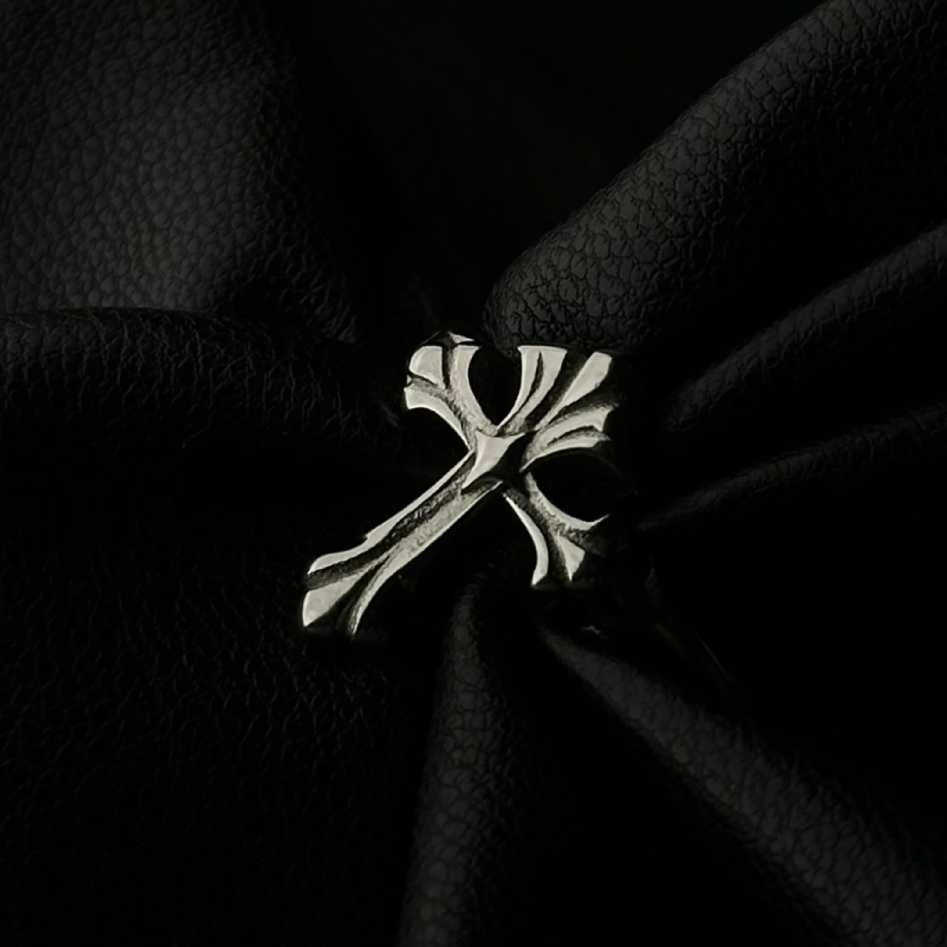 Anillo de acero inoxidable 'Follow Ring Lil Cross' con diseño de cruz en relieve, de la marca Follow God, exhibido sobre tela negra texturizada