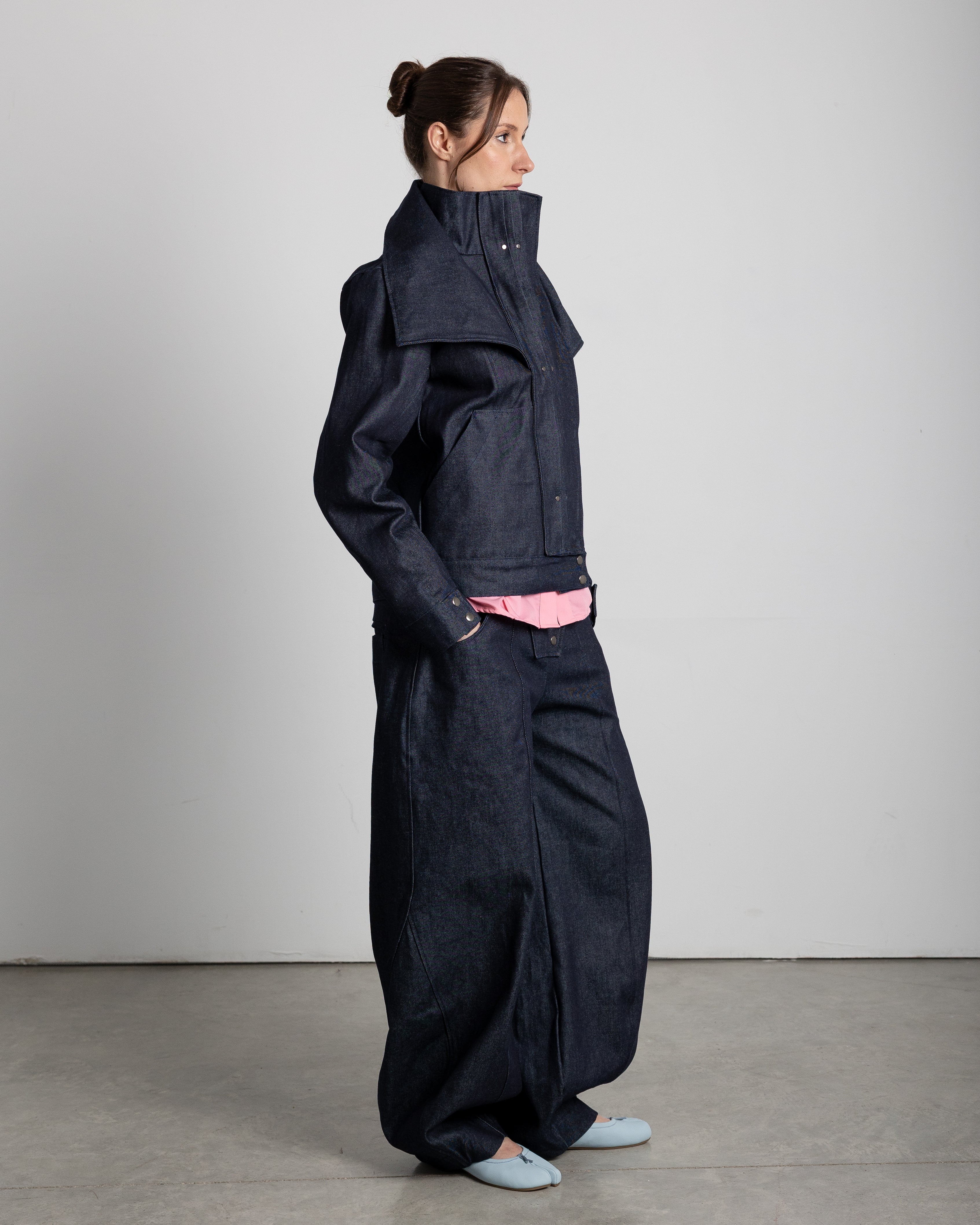 Jacket with a high collar and adjustable lapels. Pleated placket with silver studs covering the zipper. Front pockets.